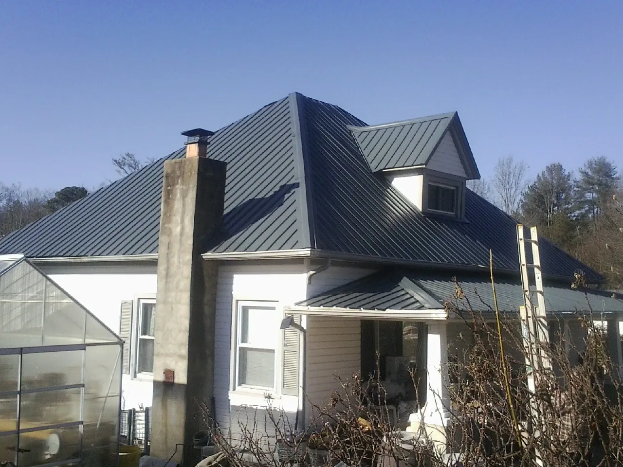 Dark blue standing seam metal roof on a white farmhouse with dormer — Slate & Tile Roof Repair by Roofing Brothers in Inglewood