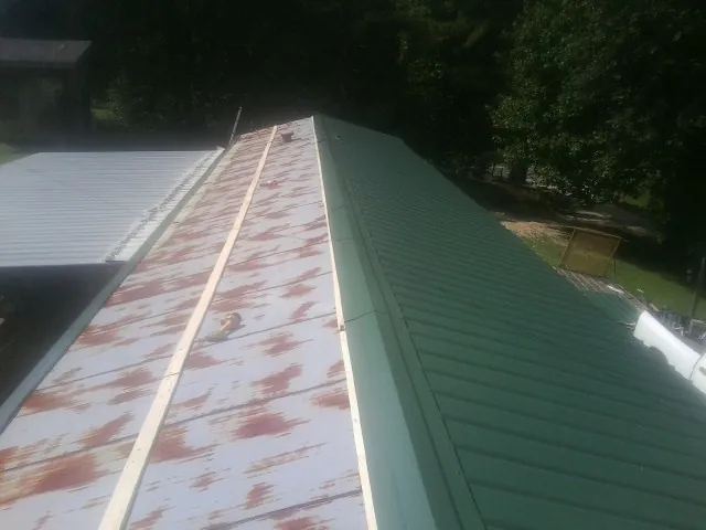 Old rusted panels beside newly installed green metal roofing — Wind Damage Roof Repair by Roofing Brothers in Inglewood