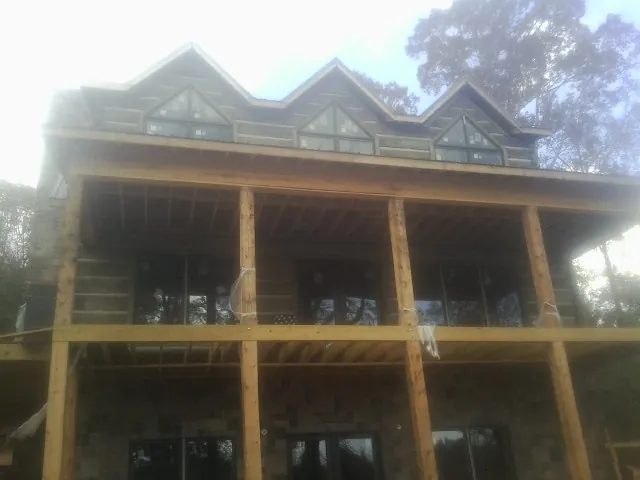 Dormers and porch framing on a large log home under construction — Roof Coating work by our crew in Inglewood