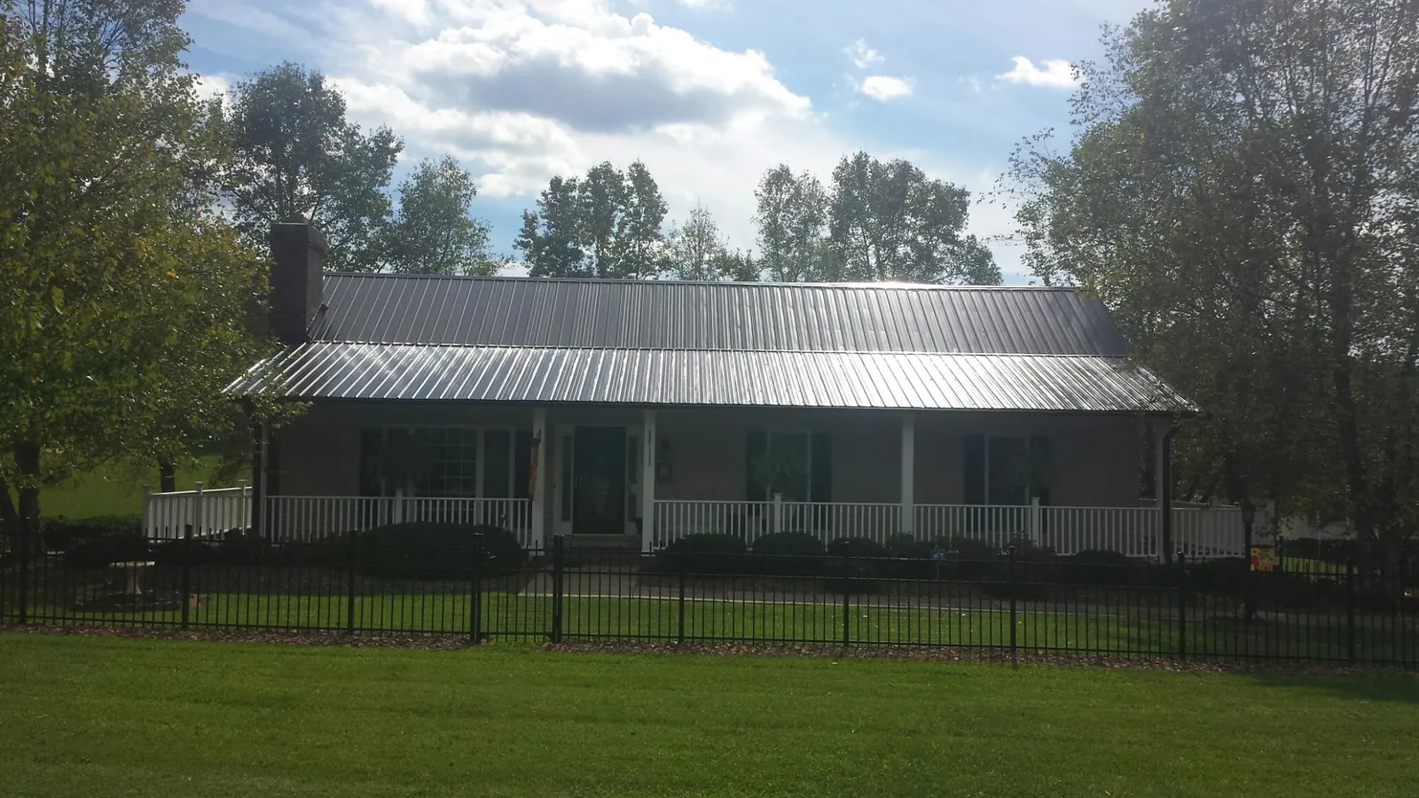 Gray metal roof on a brick ranch with a full width front porch — Gutter Guard Installation work by our crew in Inglewood