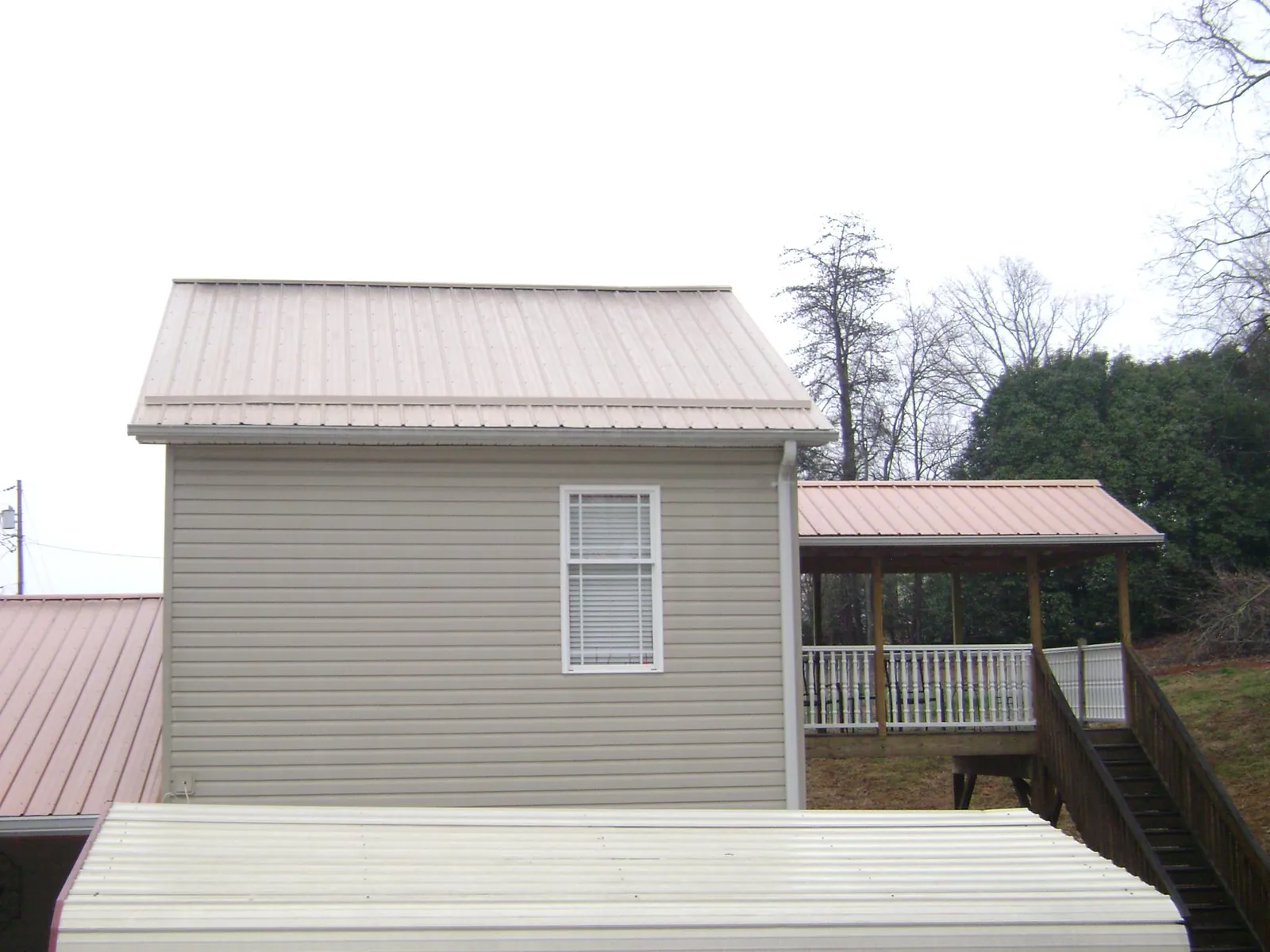 Tan metal roofs on a two story addition and attached porch, from a Roof Replacement job in Inglewood